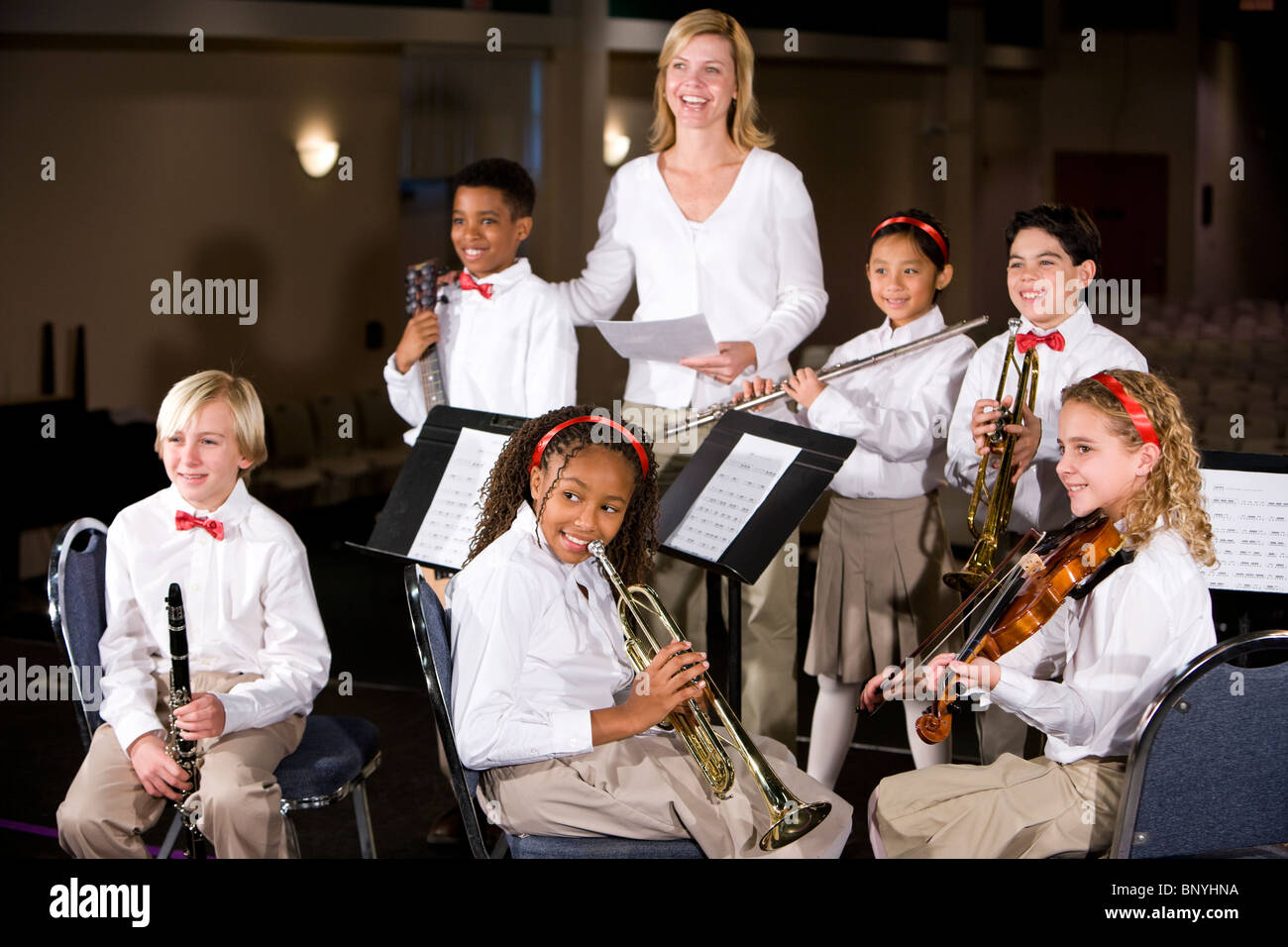 School children playing musical instruments in band with teacher Stock