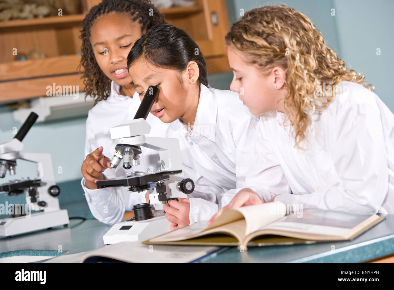 Elementary school children in science class using microscope Stock
