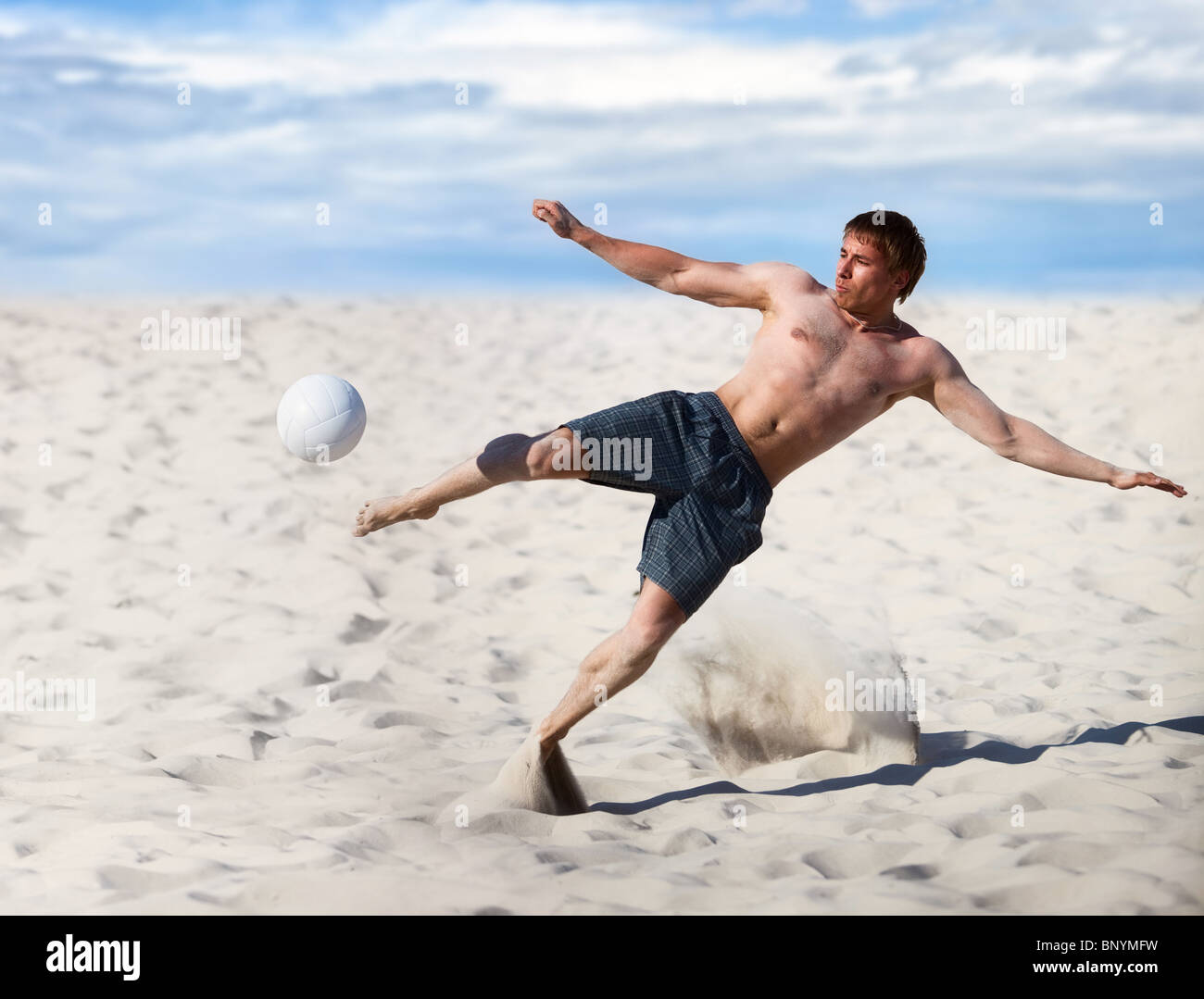 Young man playing soccer on beach. Stock Photo