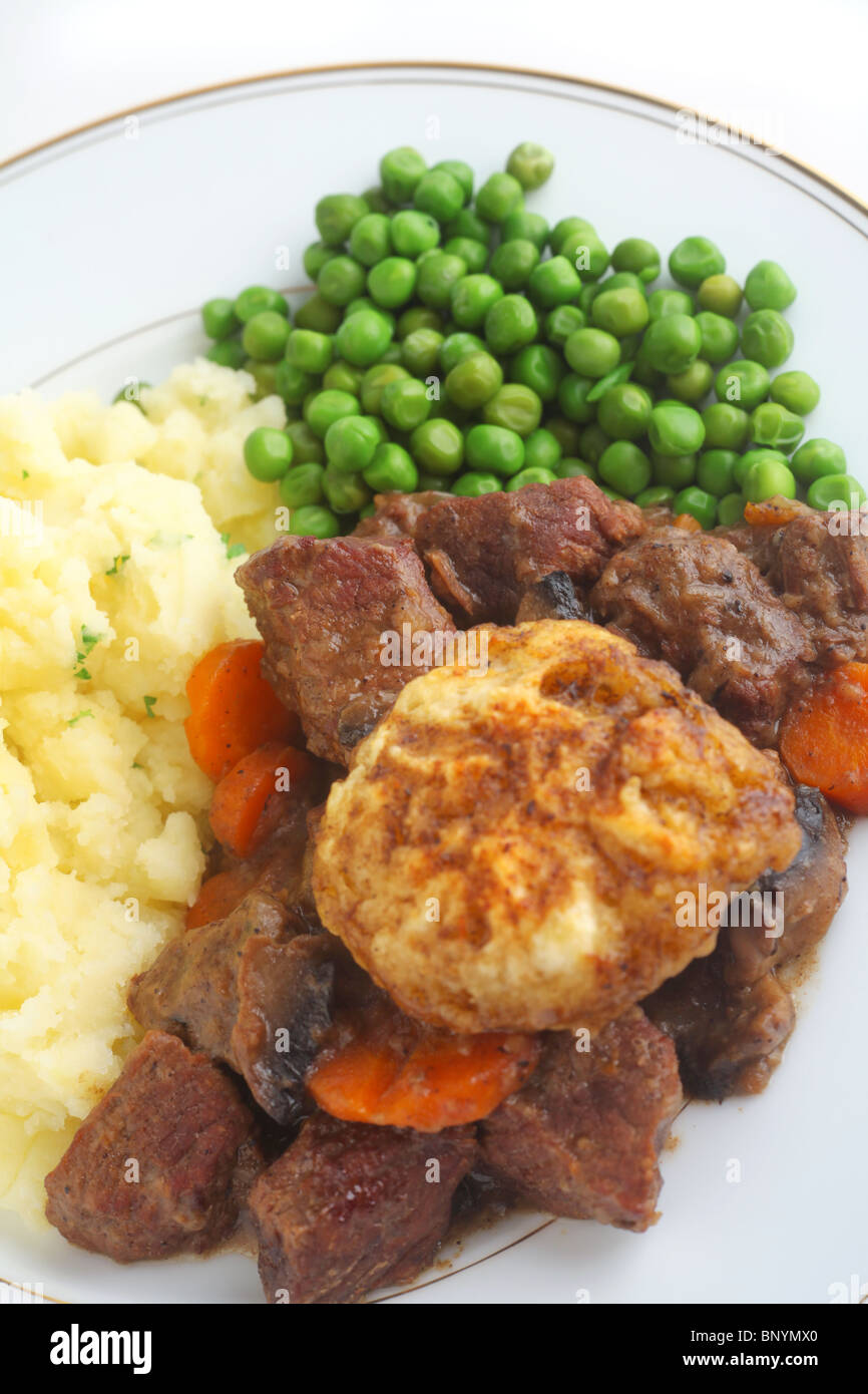 Traditional British beef stew and dumpling with mashed parsley potatoes and boiled peas. Stock Photo