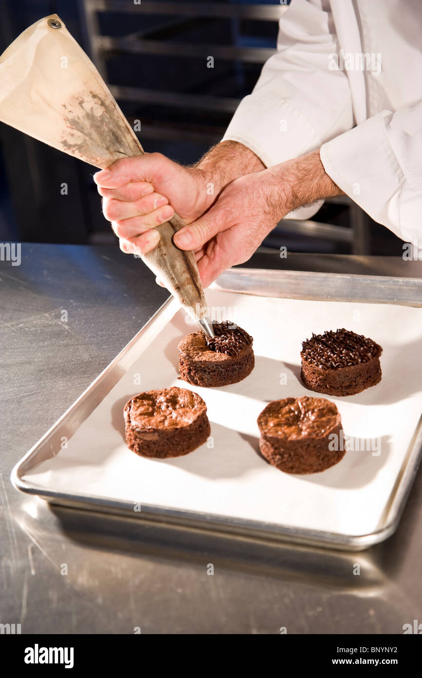 Cropped view of pastry chef decorating chocolate dessert pastries Stock Photo
