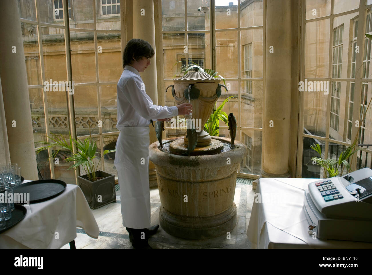 Young man serving mineral water at Roman Baths, City of Bath, Somerset