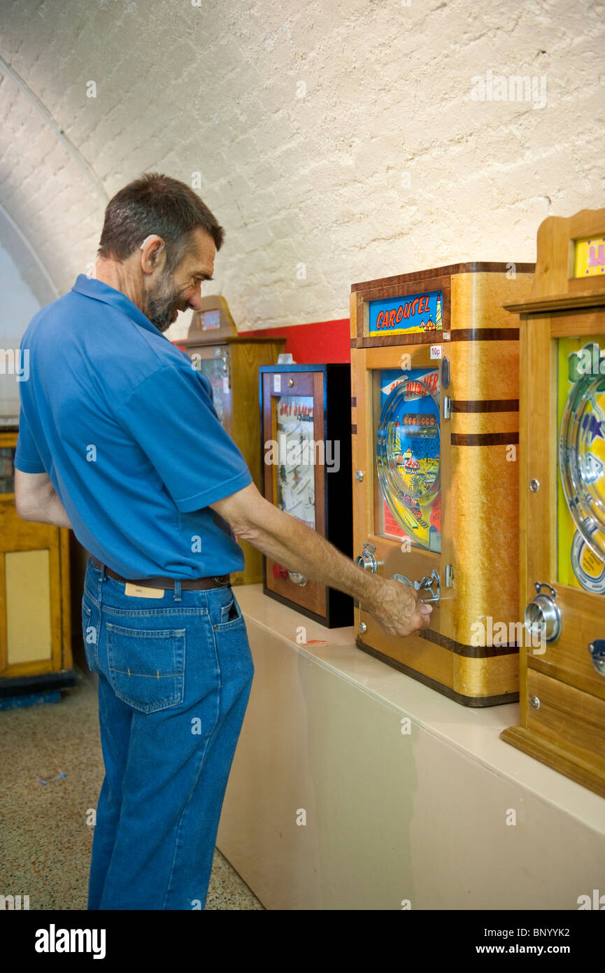 Man playing a penny slot machine in the Mechanical Memories Amusement Museum, Kings Road Arches, Brighton Stock Photo