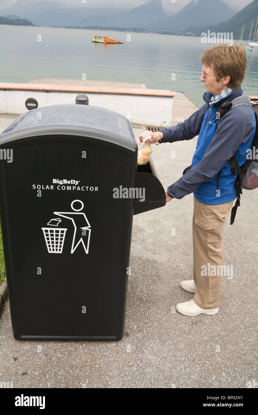 Europe Woman putting a bag of rubbish in the tray of Big Belly Solar powered litter compactor Stock Photo
