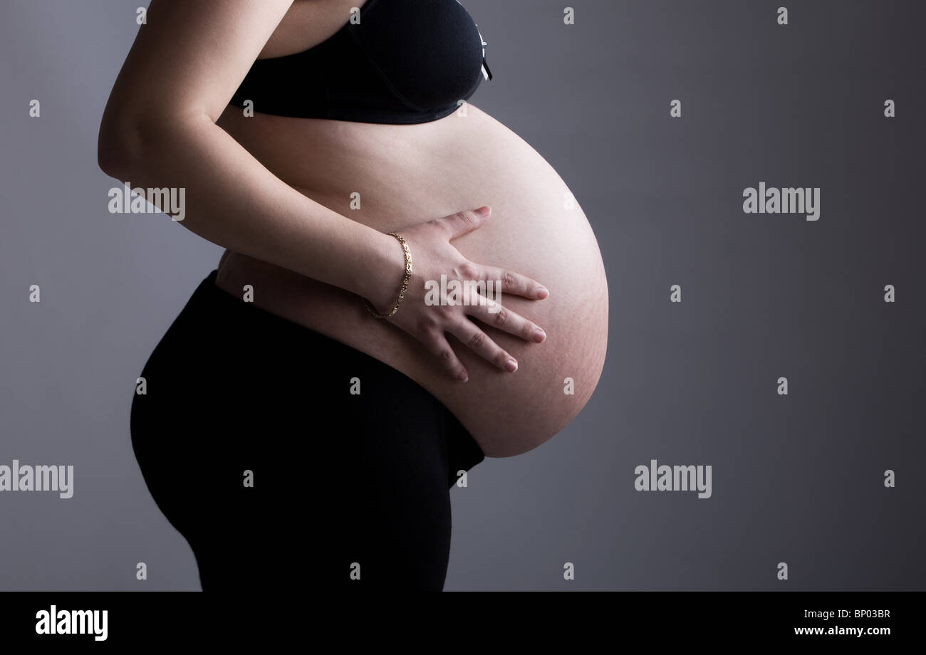 Beautiful Shot of a Heavily Pregnant Lady against Grey Background Stock Photo