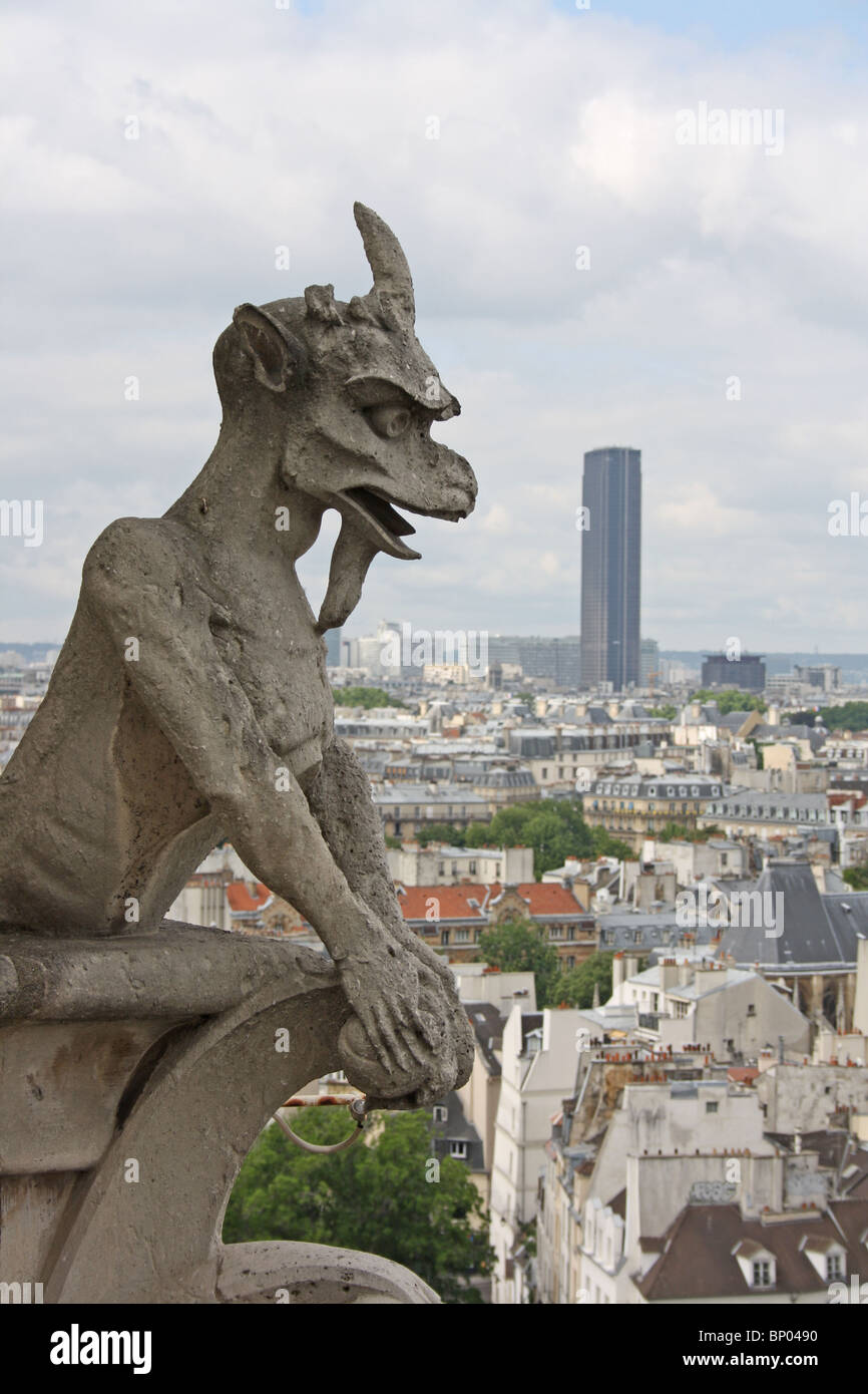 Notre Dame Cathedral, Paris.  Chimera 17, horned goat demon,  on the balcony, with Tour Montparnasse in the background. Stock Photo