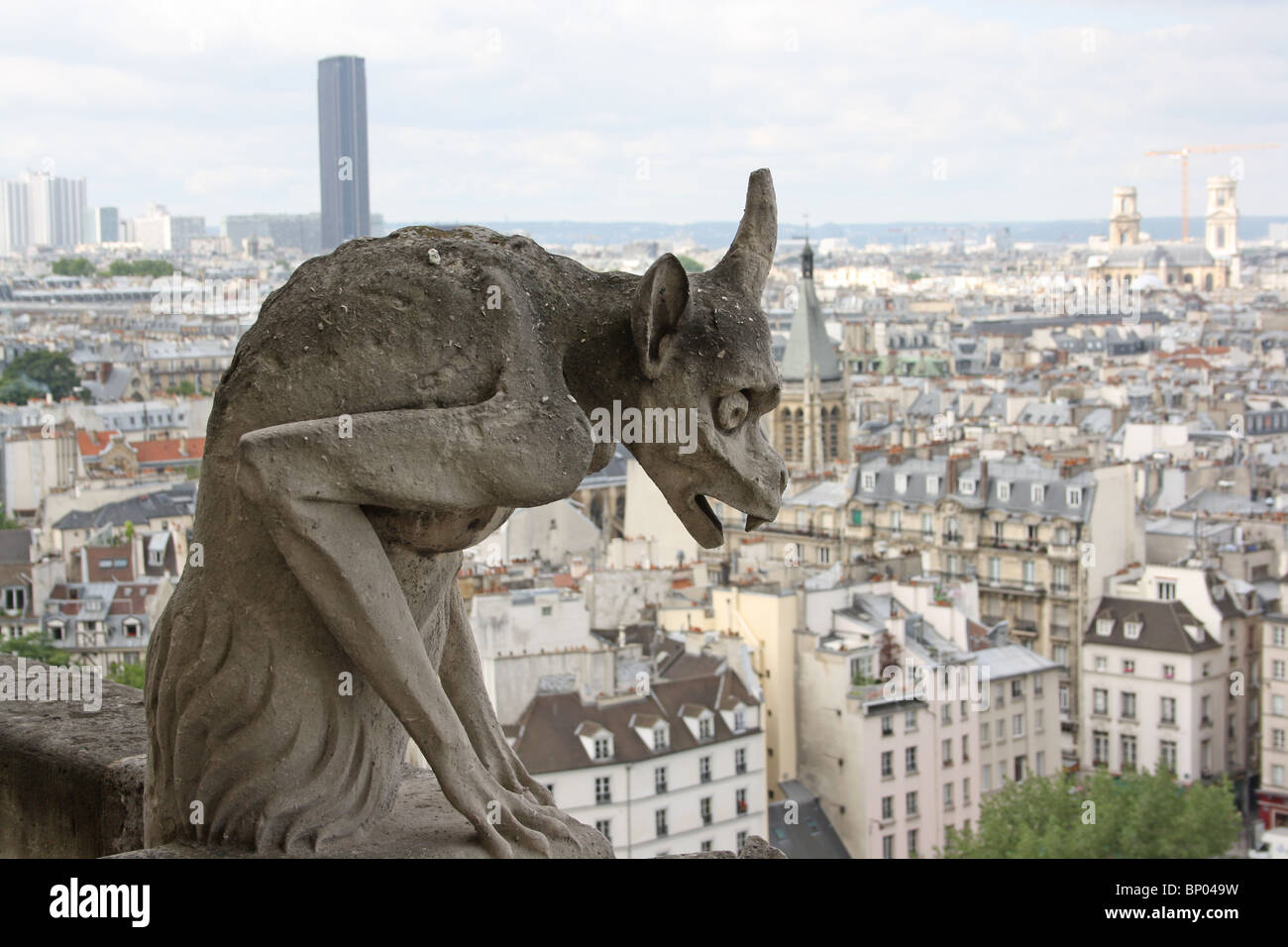 Notre Dame Cathedral, Paris.  Chimera 21, unicorn demon, on the balcony, with Tour Montparnasse in the background. Stock Photo