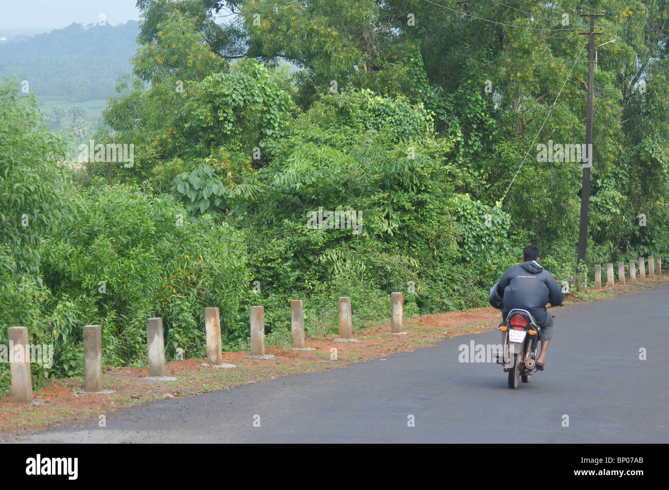 A lonely biker rides downhill behind the Mangalore airport Stock Photo