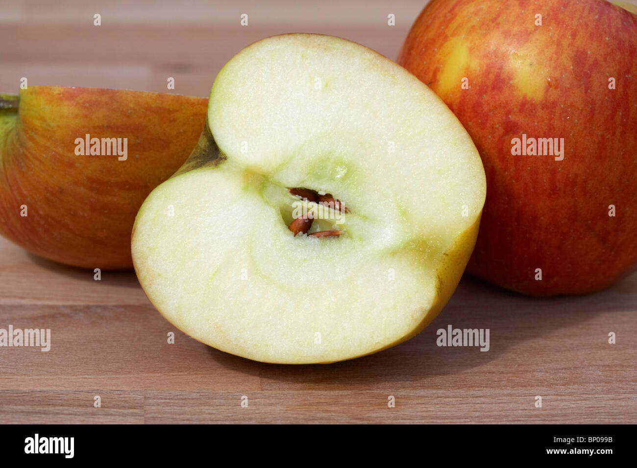 sliced halved braeburn apples on a wooden board in the kitchen Stock Photo