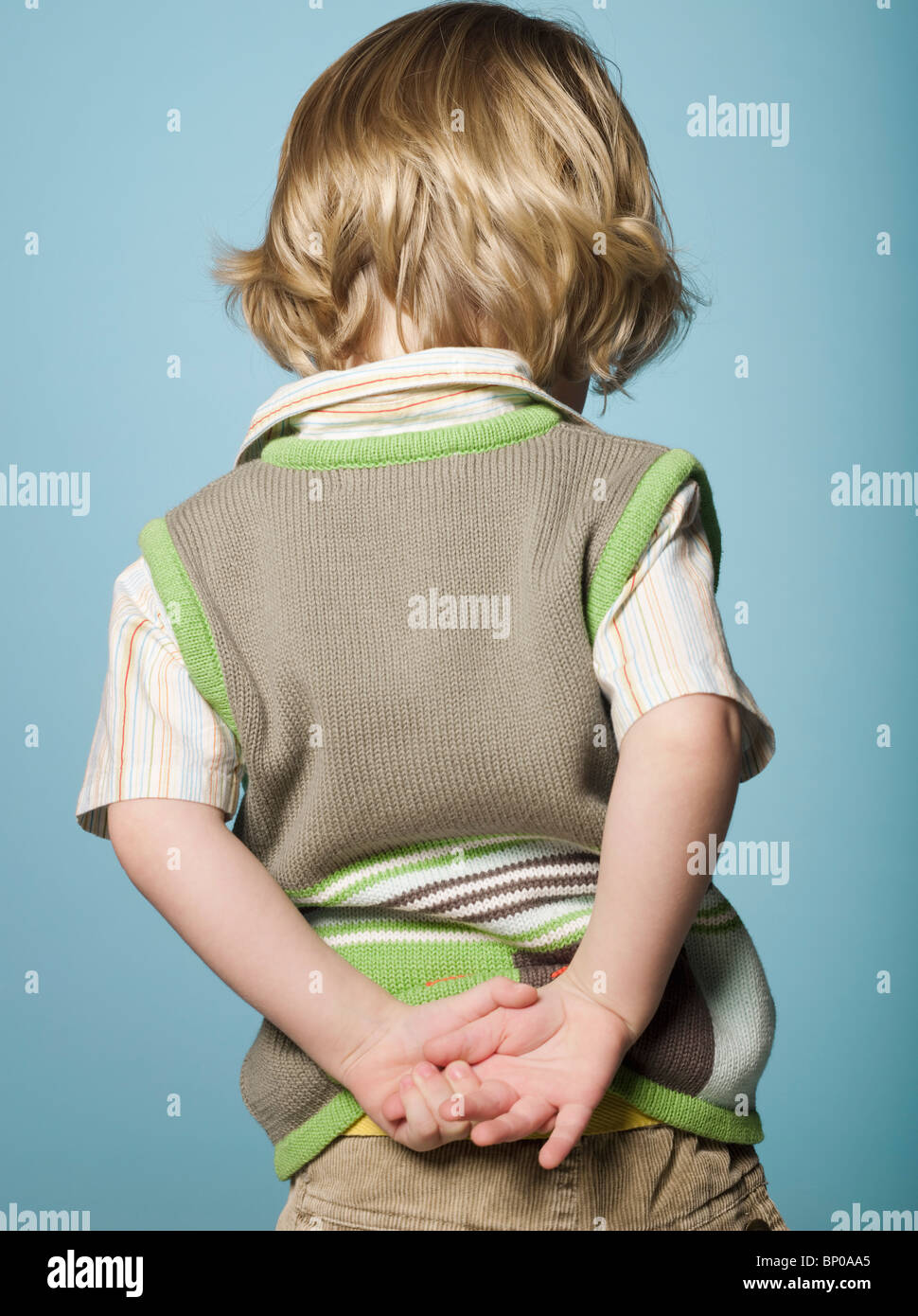 Little boy with hands behind back, rear view Stock Photo