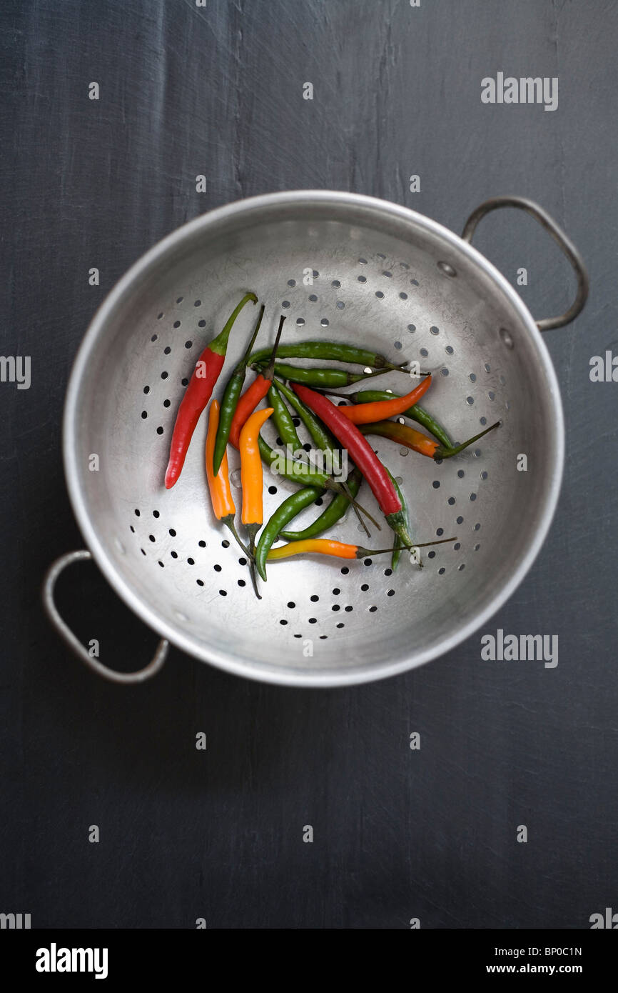 Mixed color chilies on colander Stock Photo