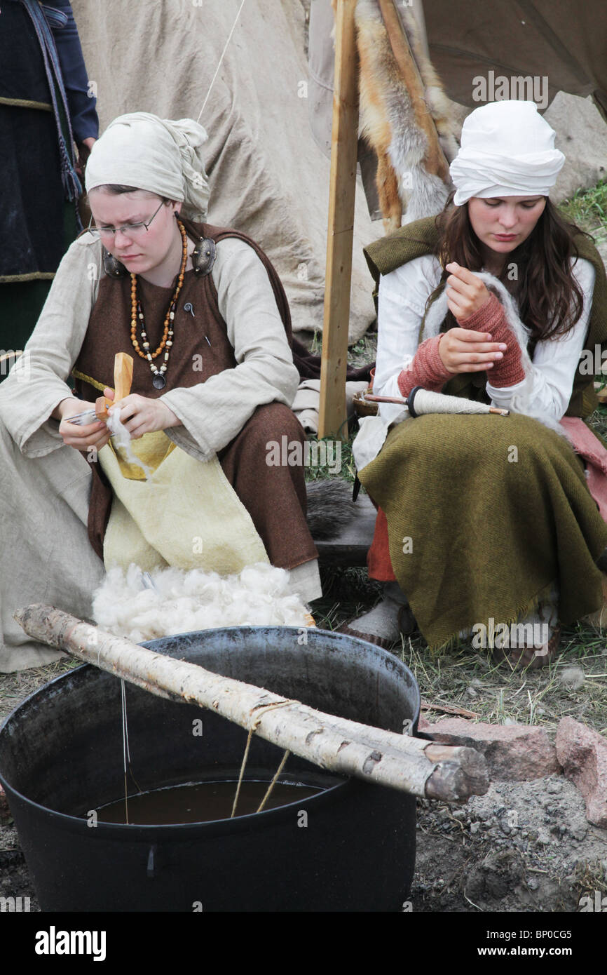 Women spin wool at Finland's biggest Viking Market Festival and re-enactment camp at Kvarnbo on land archipelago Stock Photo