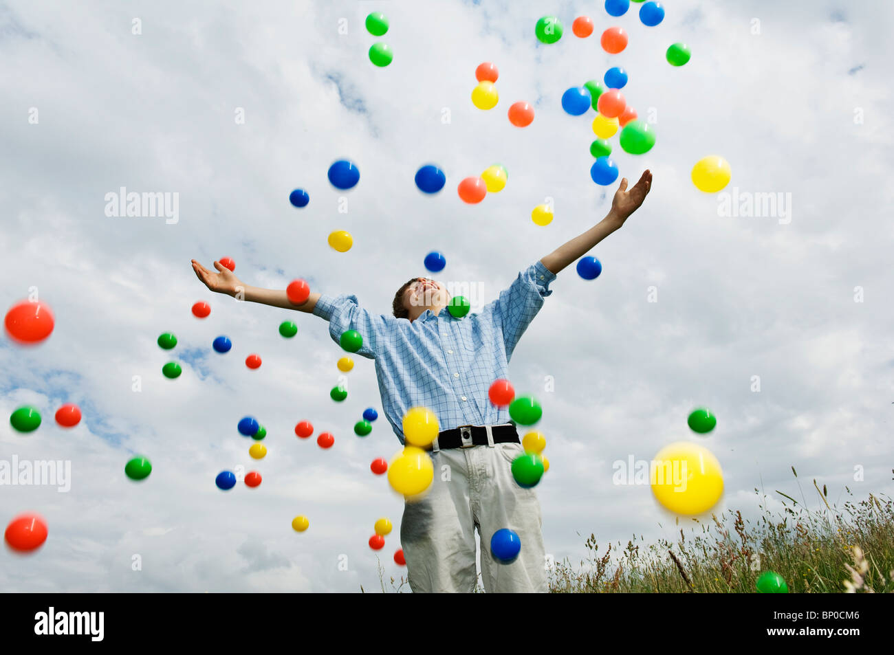 Young boy throwing colored balls Stock Photo Alamy