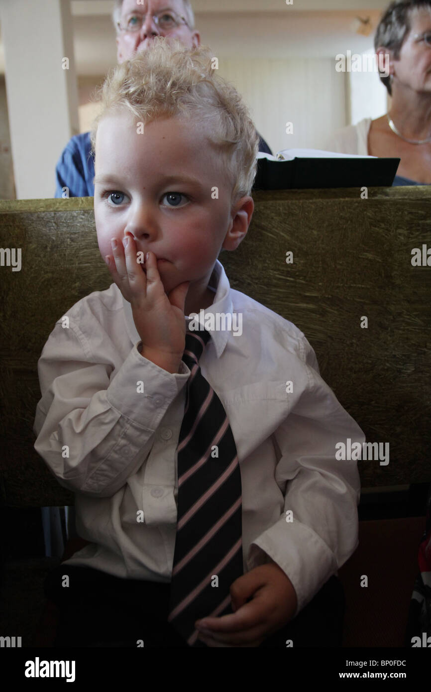 Little boy toddler in party clothes white shirt tie smartly dressed at church with family bored MODEL RELEASED Stock Photo