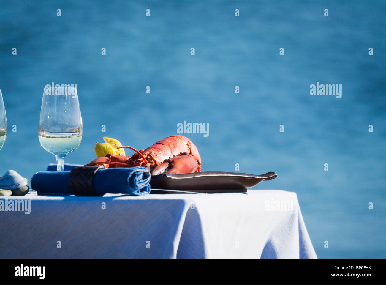 Laid table with lobster and white wine on seaside Stock Photo - Alamy