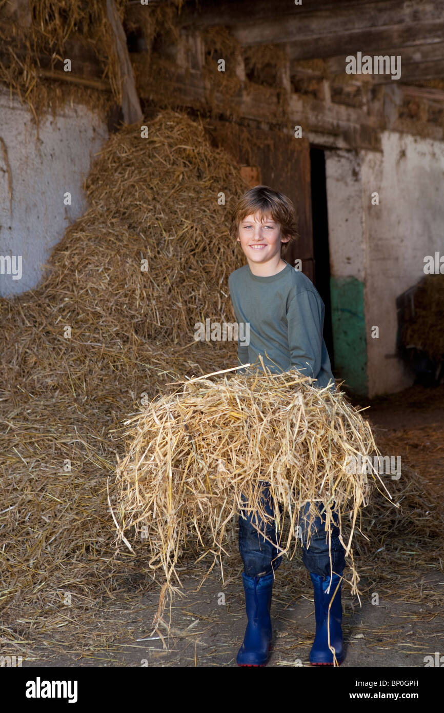 Boy with hay on fork, smiling Stock Photo
