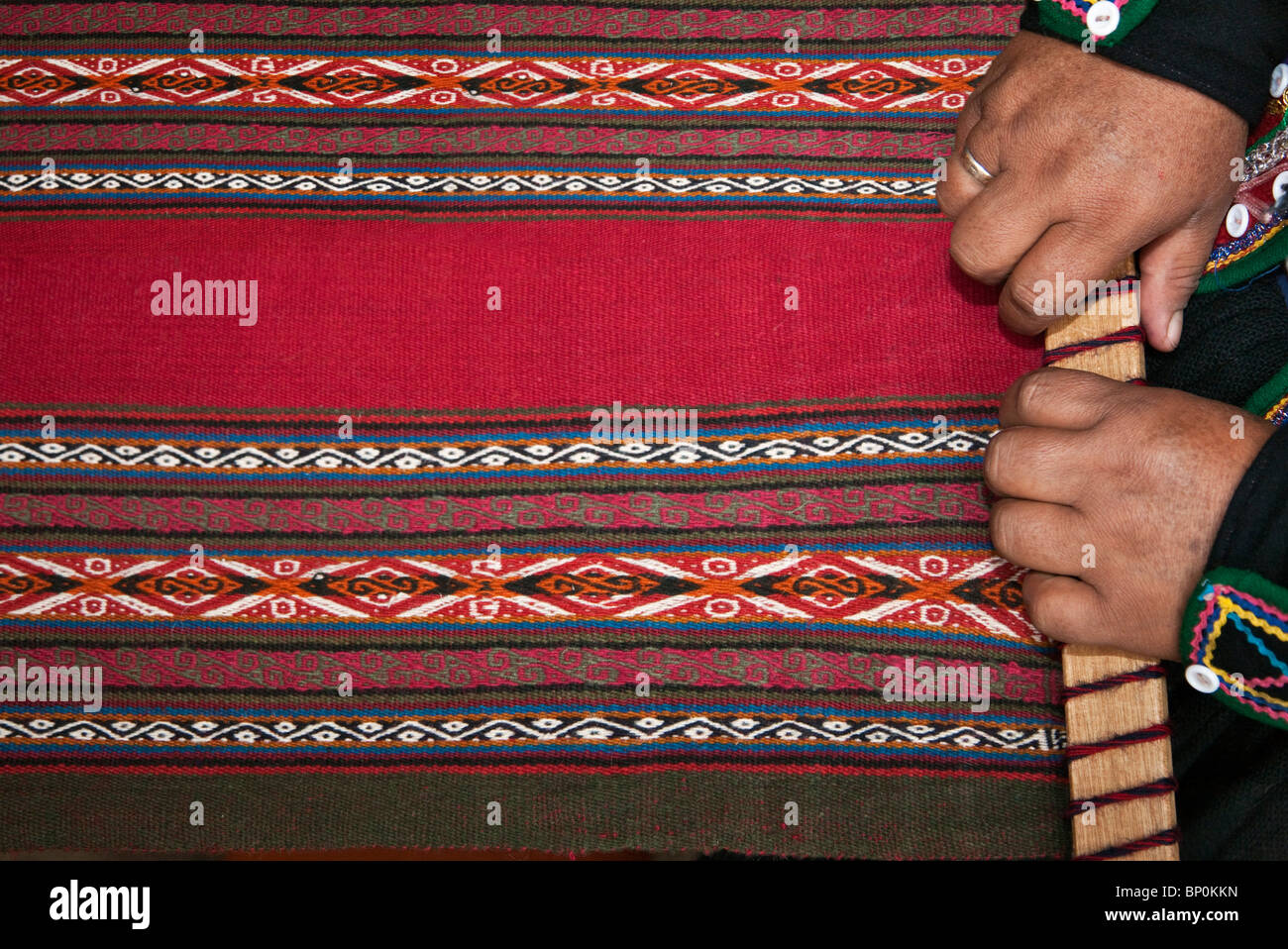 Peru, A Chinchero weaver at her loom in the process of making woollen cloth in a typical, traditional Andean design. Stock Photo