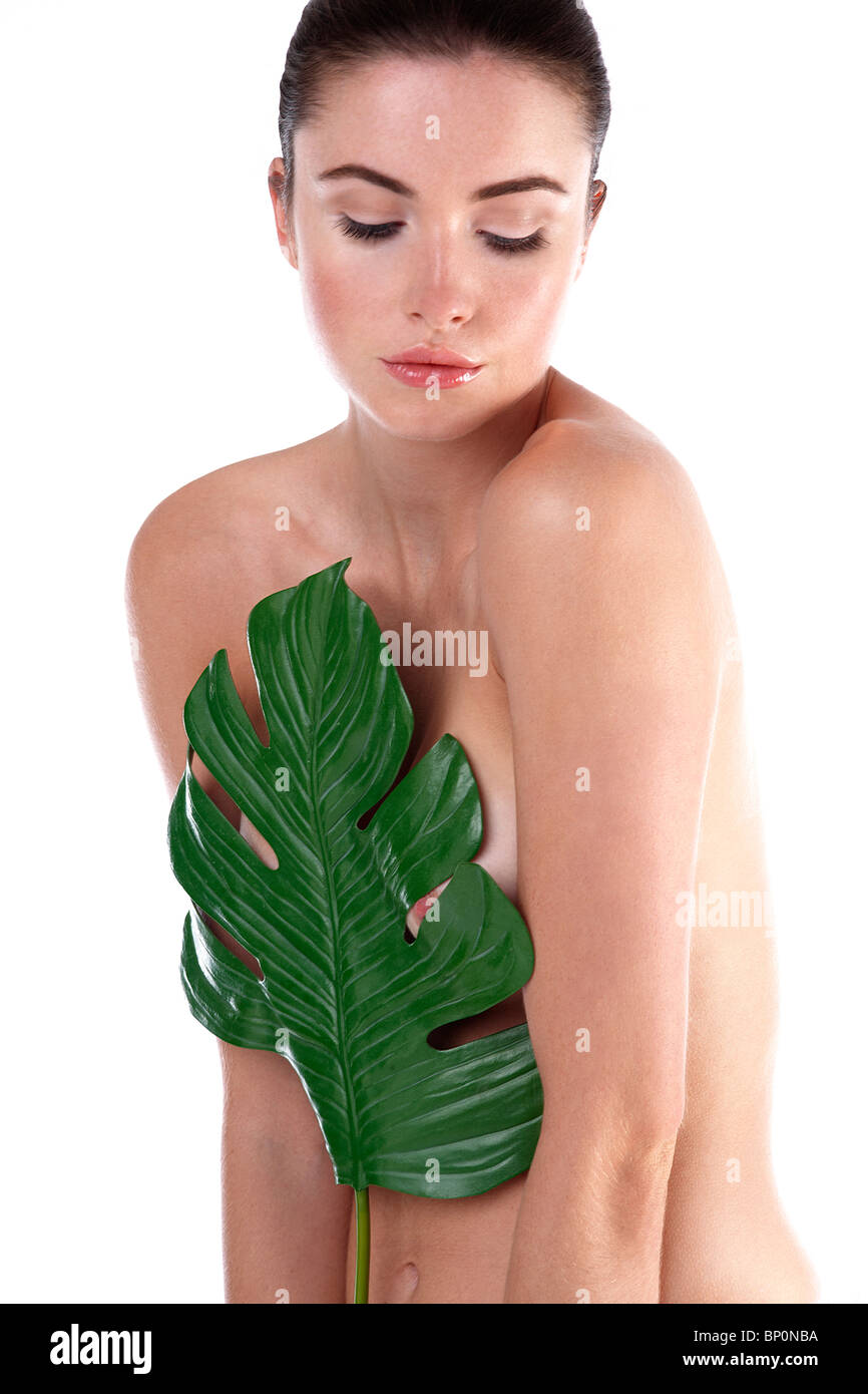 Naked woman holding leaf in front of her chest Stock Photo - Alamy