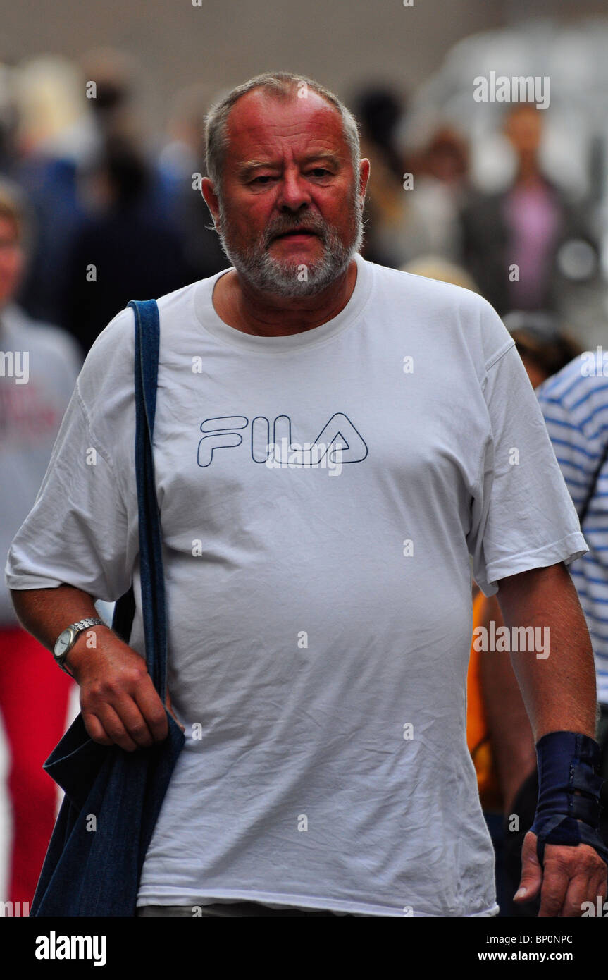 Mature Caucasian man in white t shirt carrying a shoulder bag in London Stock Photo