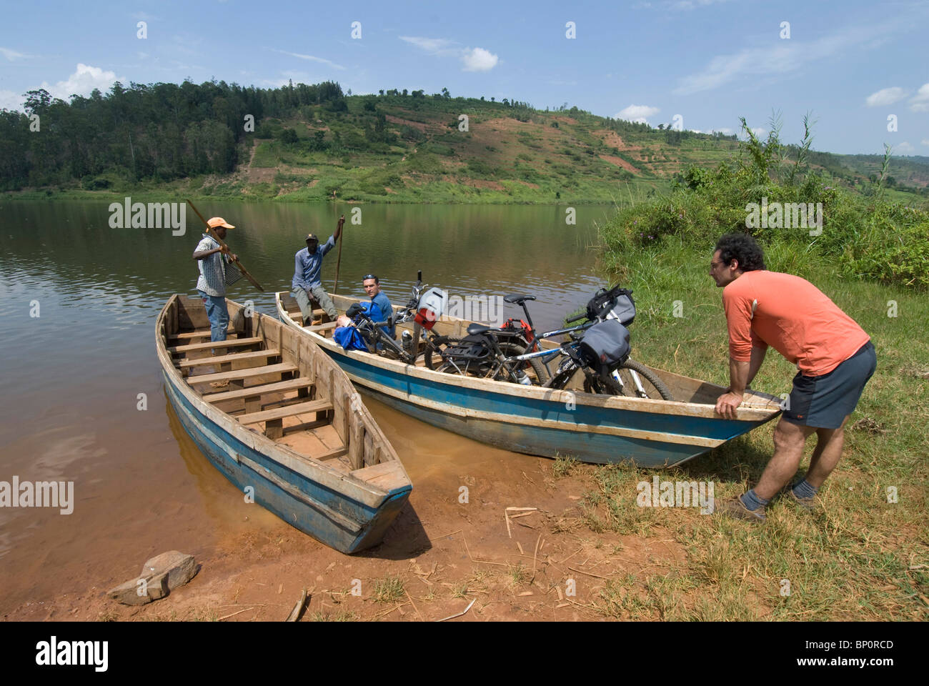 2 hommes européens prennent avec leur vtt une barque afin de traverser le lac MUHAZI au nord de KIGALI Stock Photo