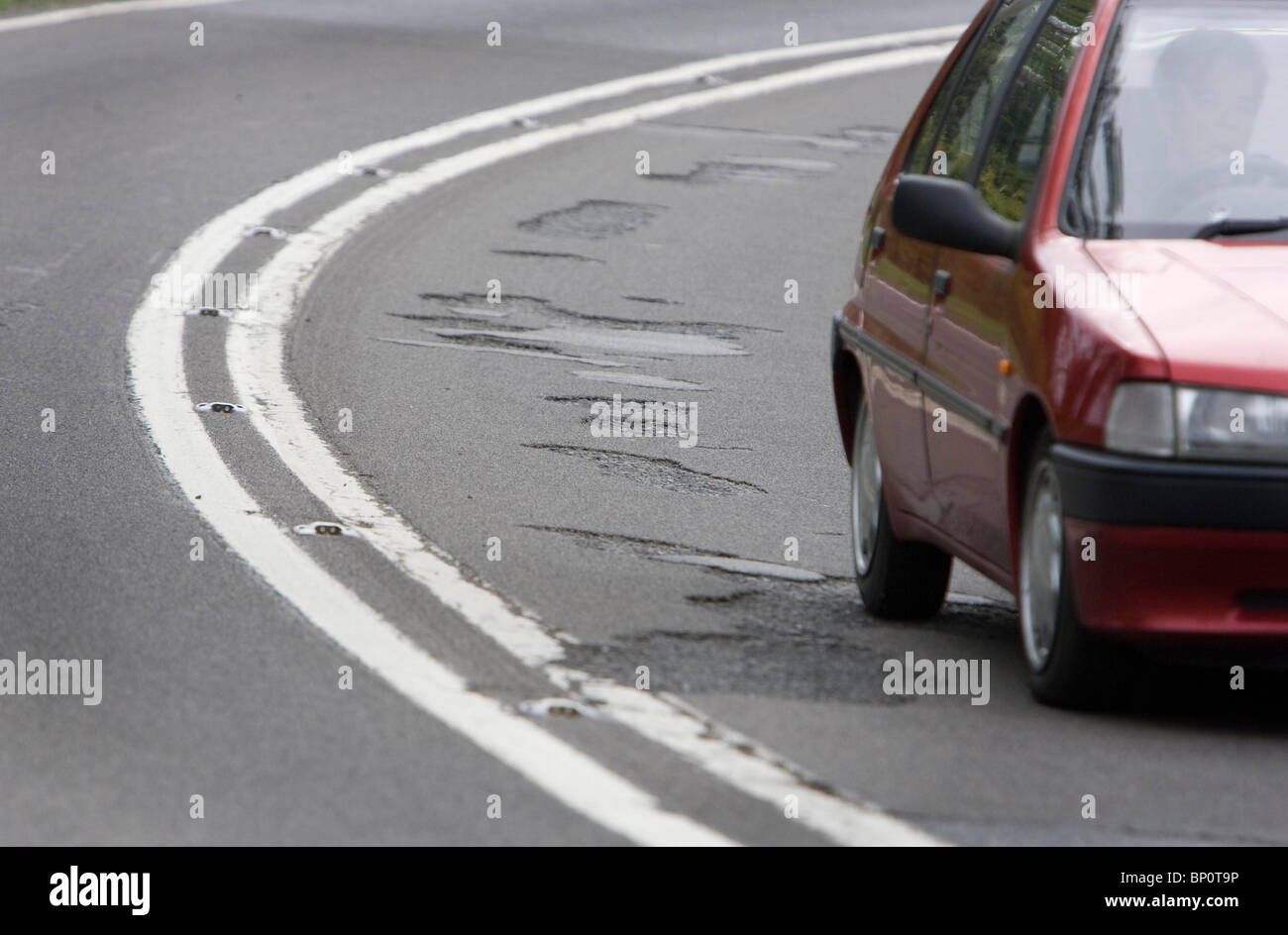 A motorist drives past a number of potholes on a country road. Picture by James Boardman. Stock Photo