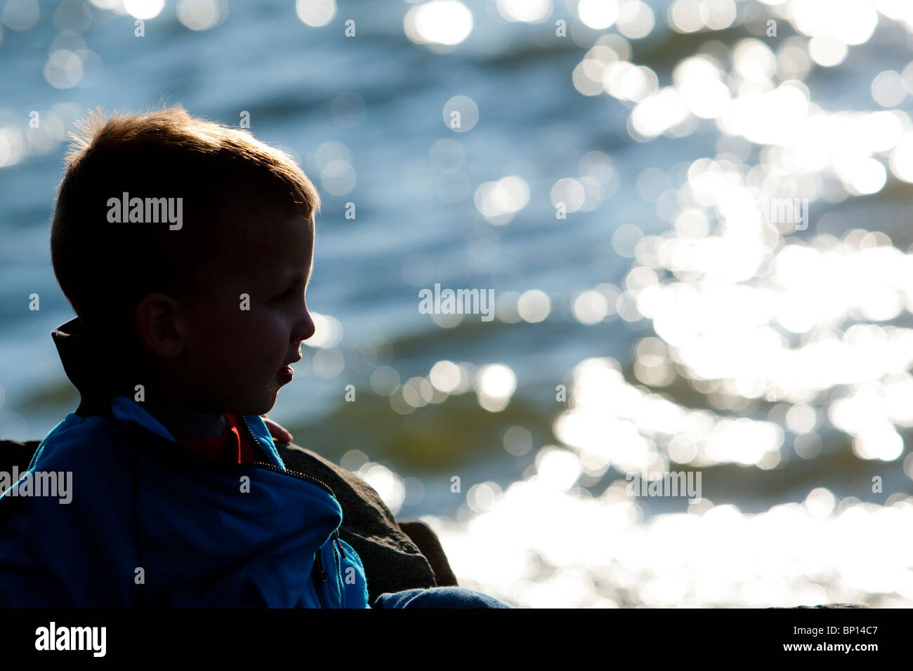 A two years old kid looks at the sun setting on the StLawrence river