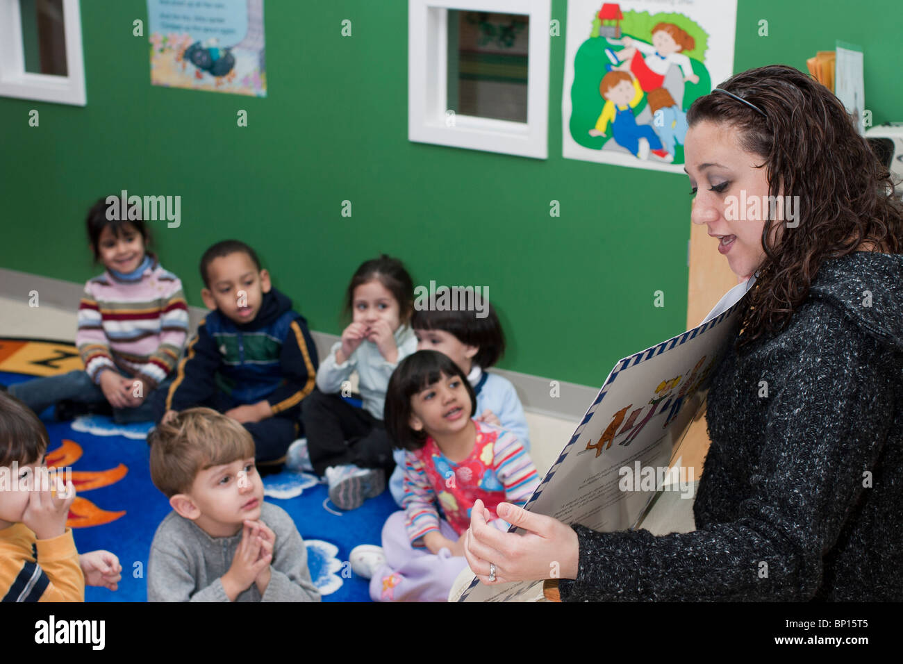 Preschool Classroom Preschool teacher reading a book to her class Stock