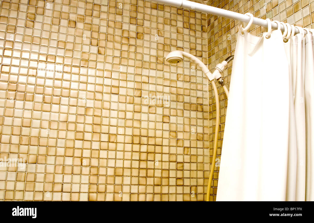 Old tiled shower stall and shower curtain in bathroom Stock Photo
