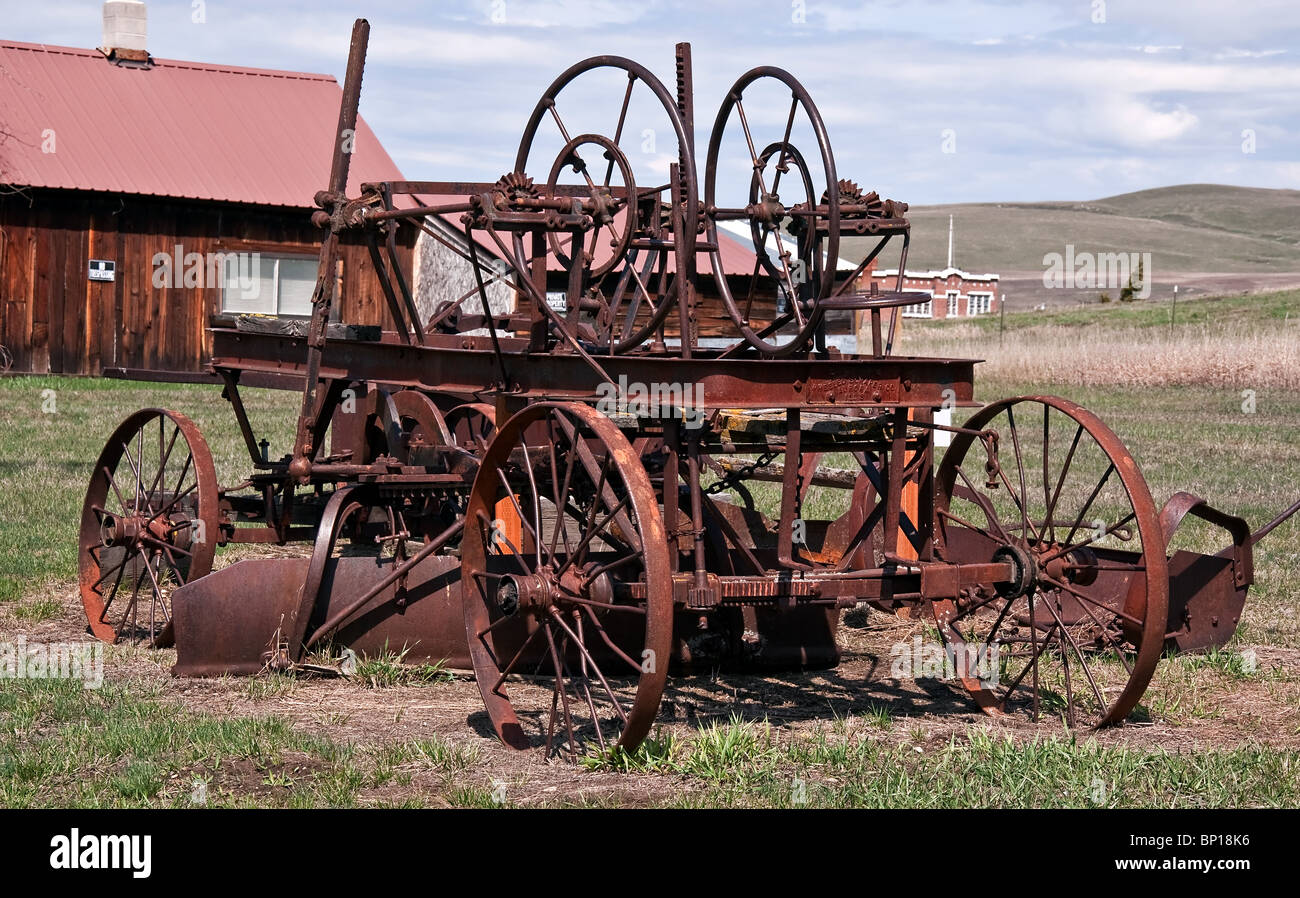 Rusty, tractor type farm equipment, set in a rural setting with range land in the background. Stock Photo