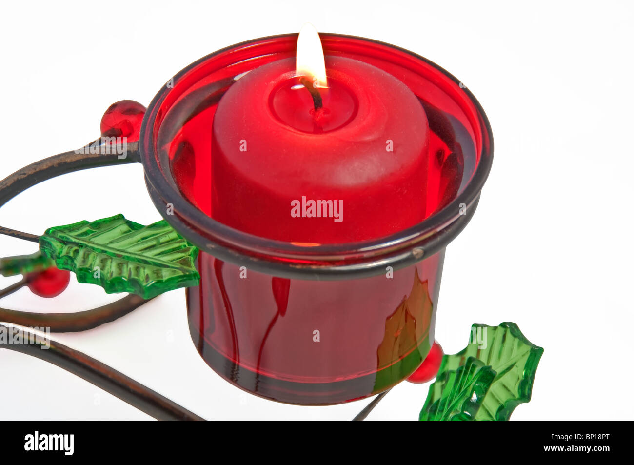This red votive candle is lit and burning in a Christmas holder that is