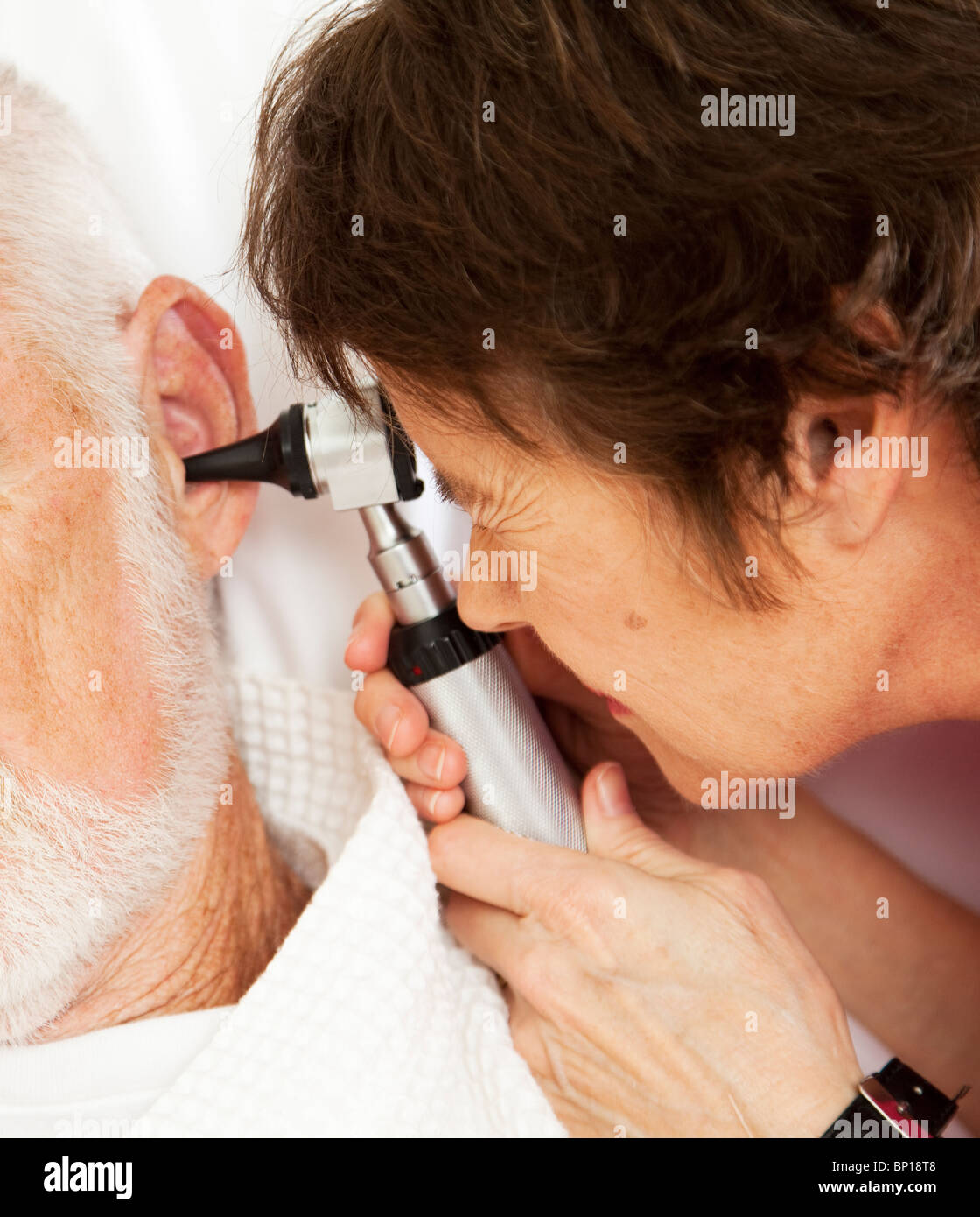 Closeup of nurse or doctor looking in a patient's ears with an otoscope ...