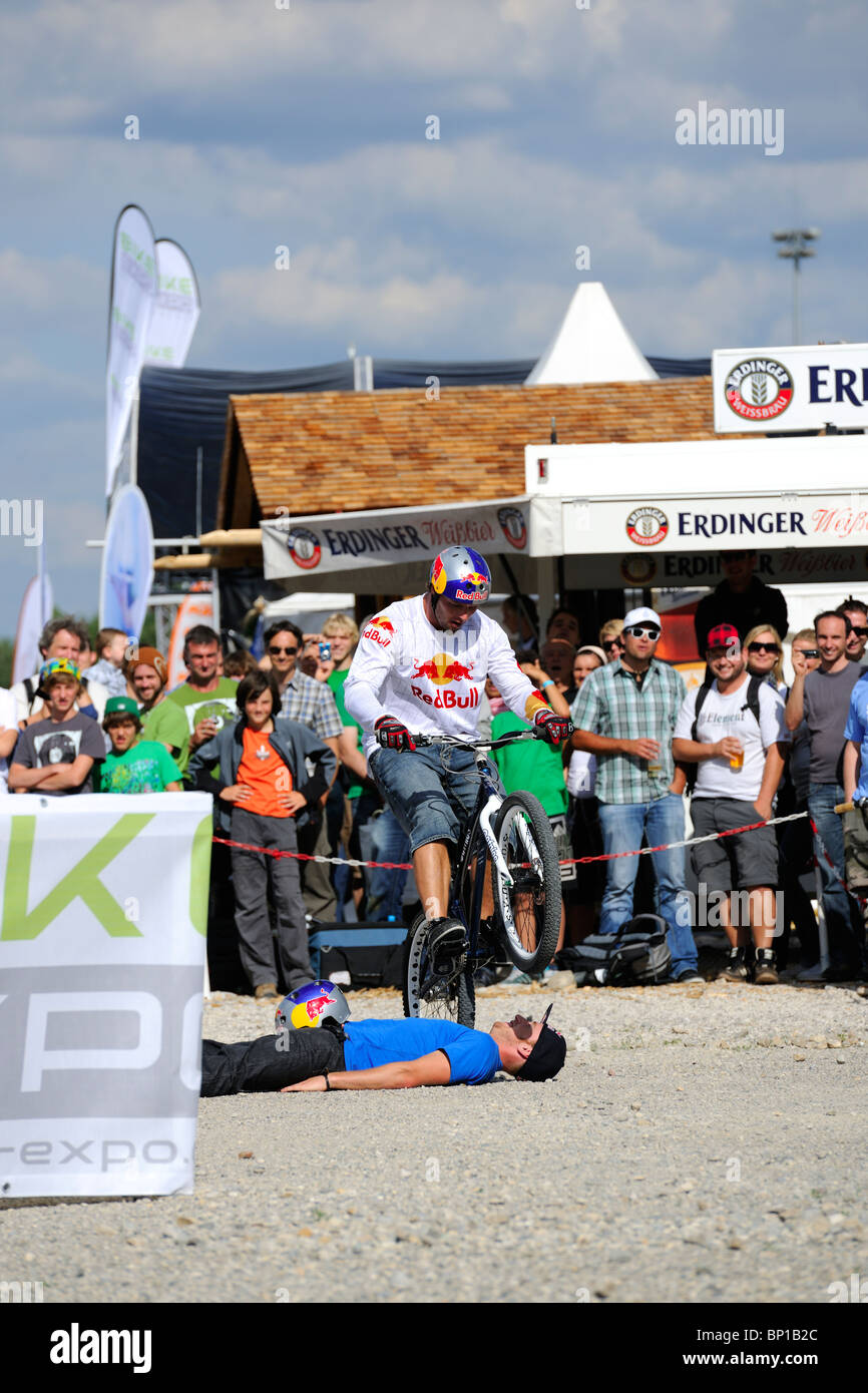 World Champion Trial Biker Petr Kraus at the Bike Expo in Munich jumping over Danny MacAskill (a Street Trials Pro Rider). Stock Photo