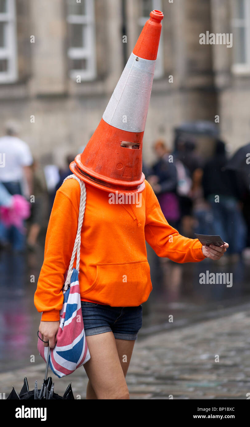 Girl with parking cone over her head handing out leaflets in Edinburgh Fringe Festival. Stock Photo