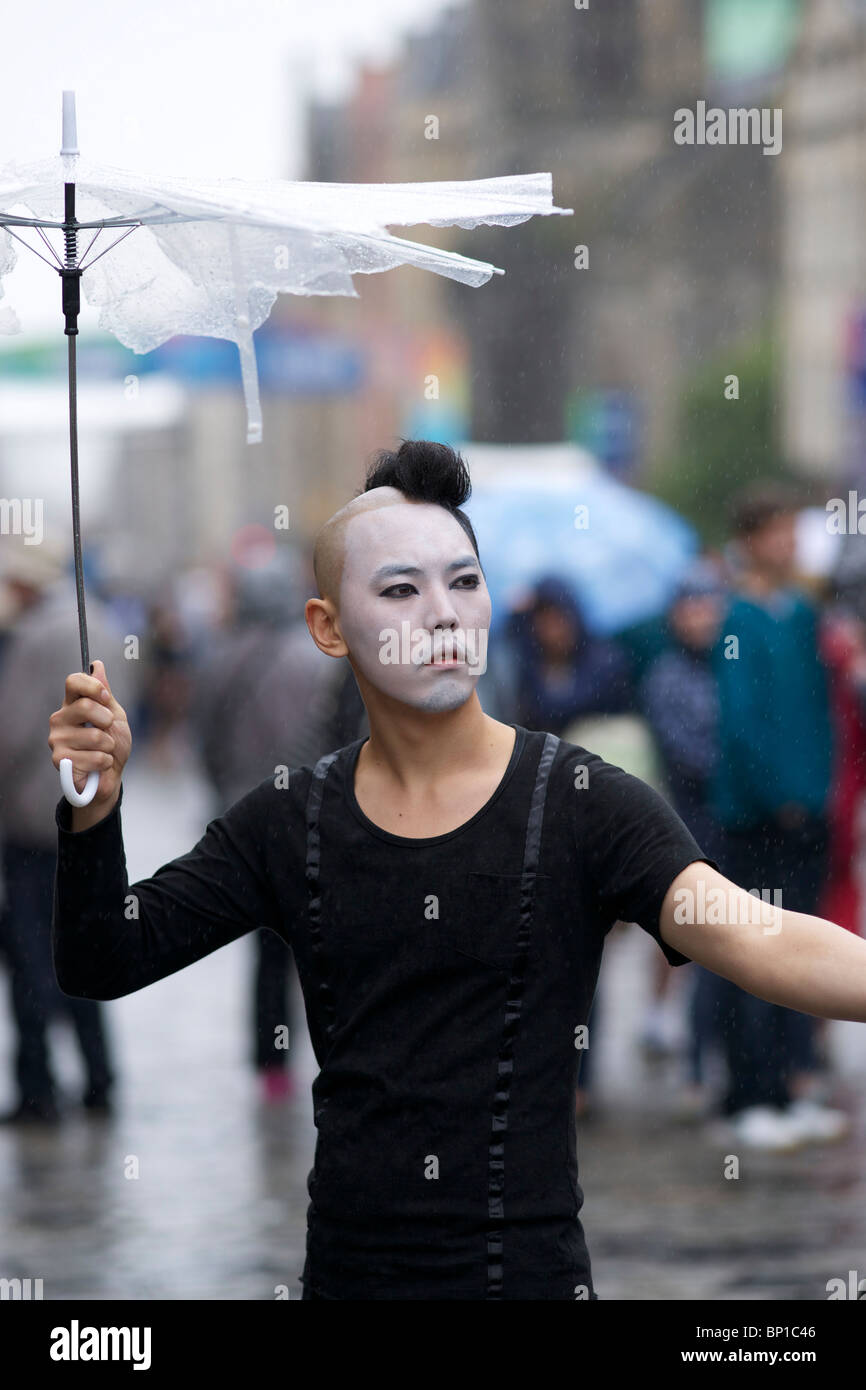 Male Performer in High Street Edinburgh holding umbrella during the rain. Stock Photo