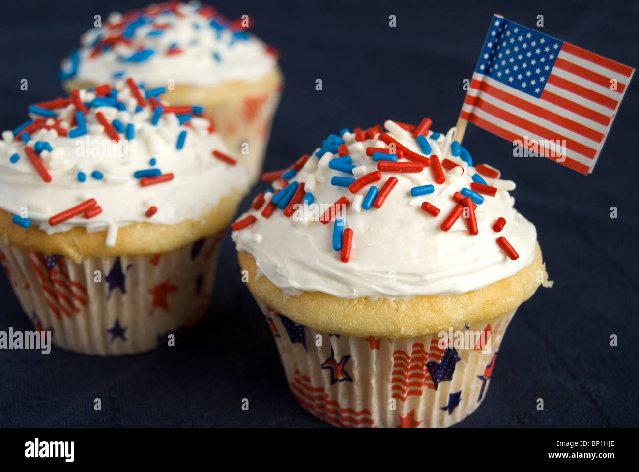 Three cupcakes are decorated with red, white and blue sprinkles. Front ...