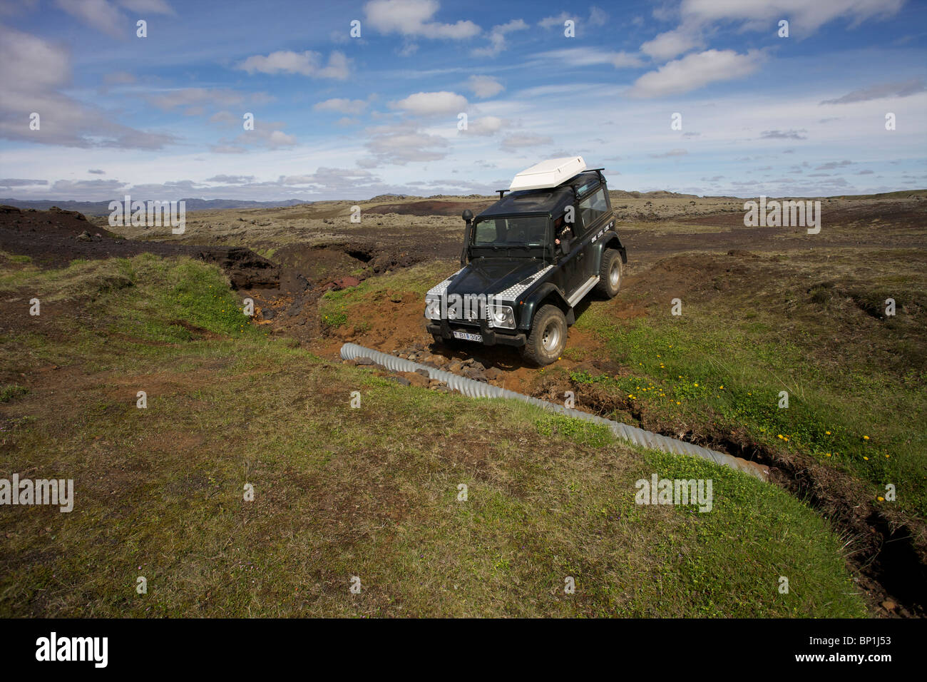 Land Rover Defender TDI goes across a washed out road in the highlands of Iceland near Laki Craters. Vatnajokull National Park Stock Photo