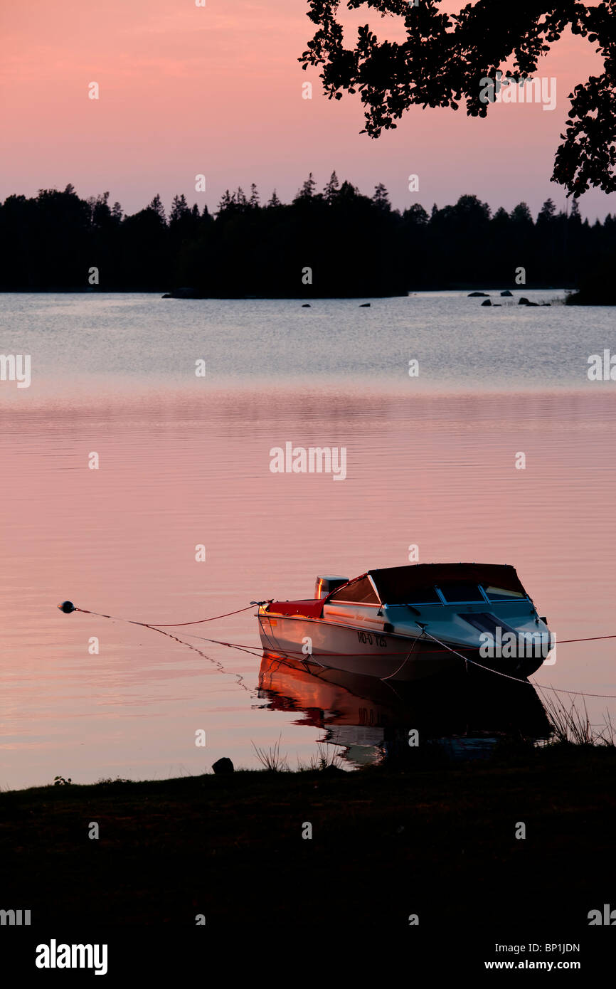 Speedboat at the beach of a lake in orange sunset Stock Photo