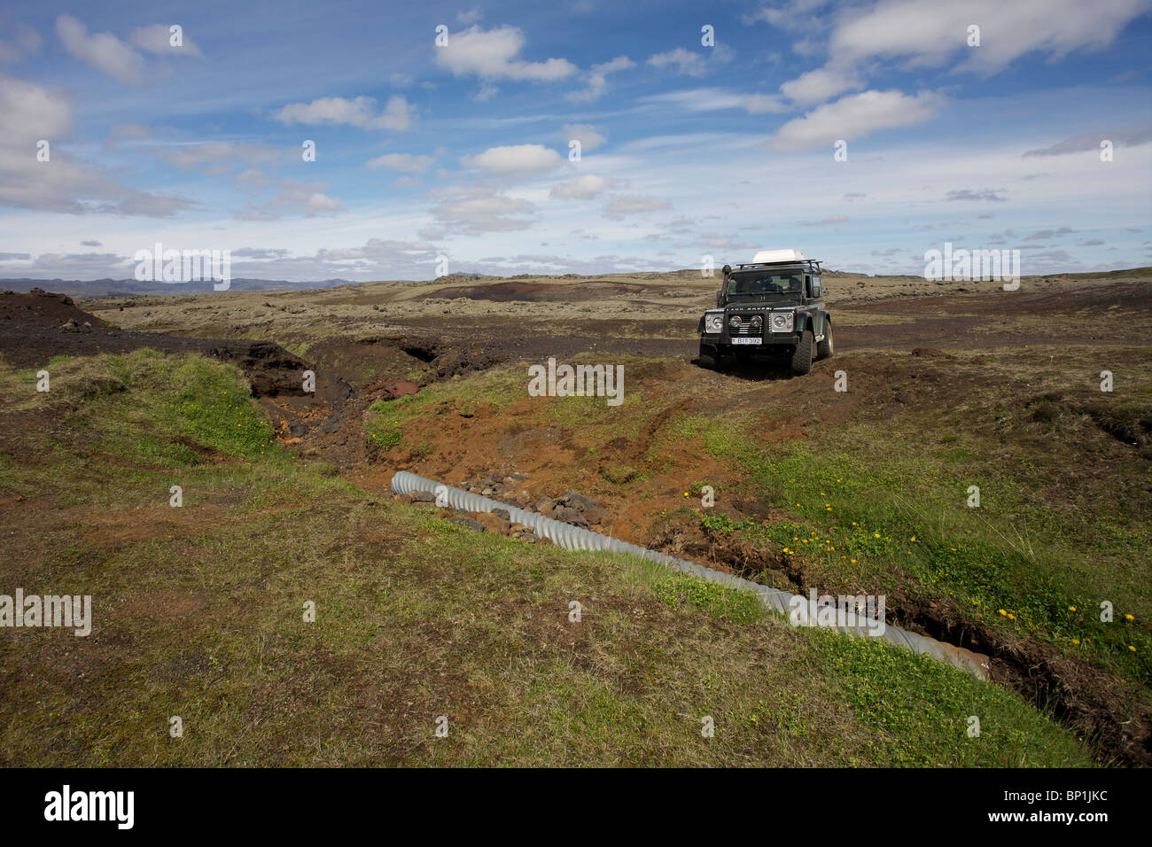 Land Rover Defender TDI goes across a washed out road in the highlands of Iceland near Laki Craters. Vatnajokull National Park Stock Photo