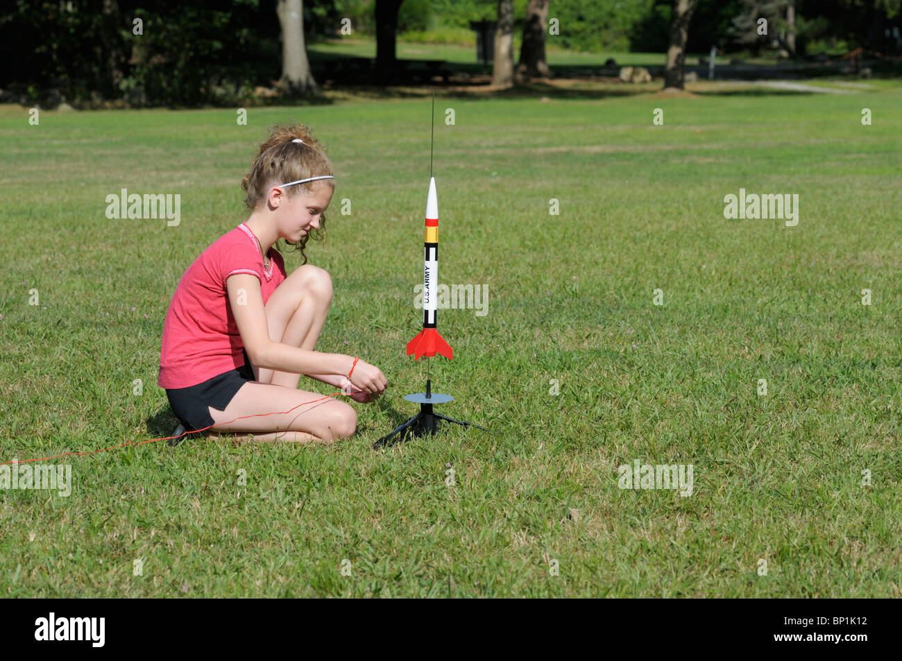 Girl, 11-12, setting up a model rocket to launch. Stock Photo
