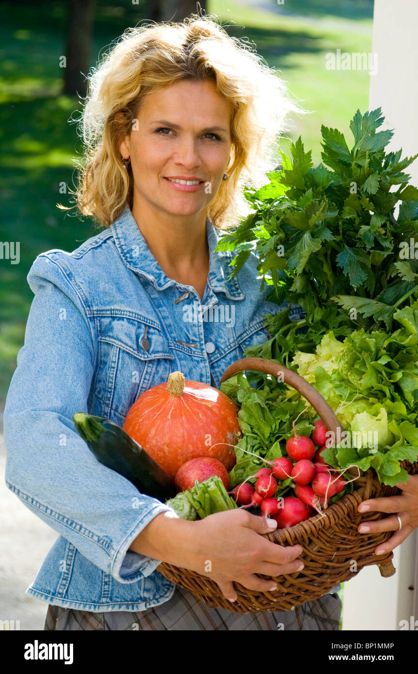Woman holding a basket of vegetables Stock Photo - Alamy