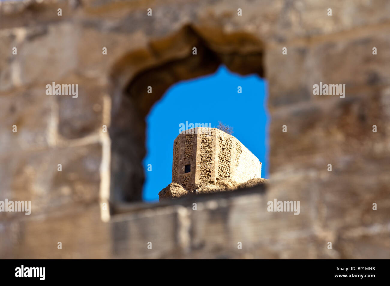 A tower of the Mardin Citadel through an old city window, Mardin, Turkey Stock Photo