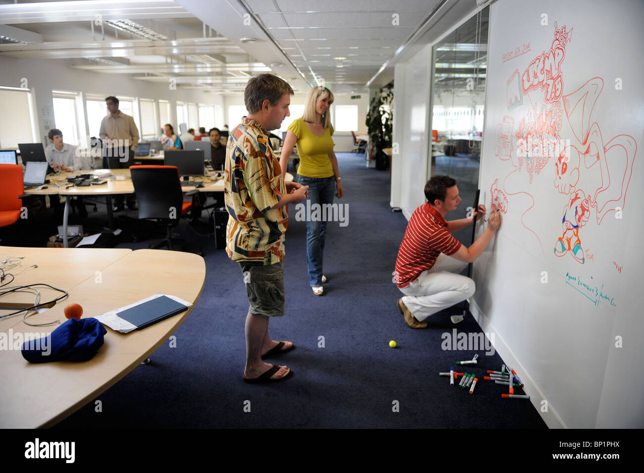 Staff at a business communication solutions provider using a white board and indoor golf to relax UK Stock Photo