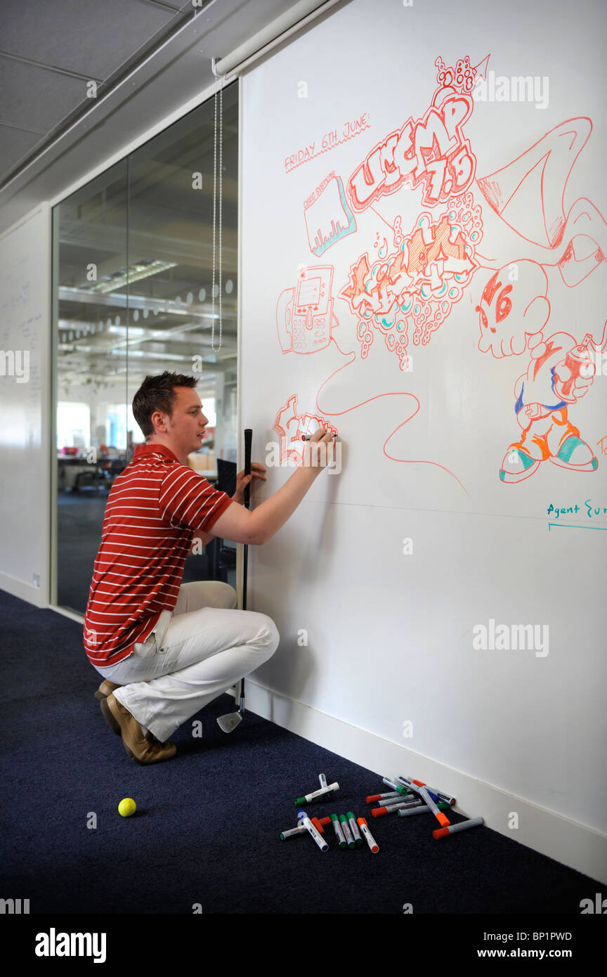 A member of staff at a business communication solutions provider draws on a white board UK Stock Photo