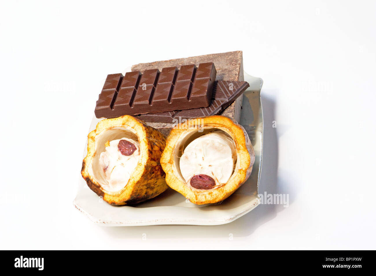 Close-up cacao fruit pod cut in halves with bars of chocolate on white background Stock Photo