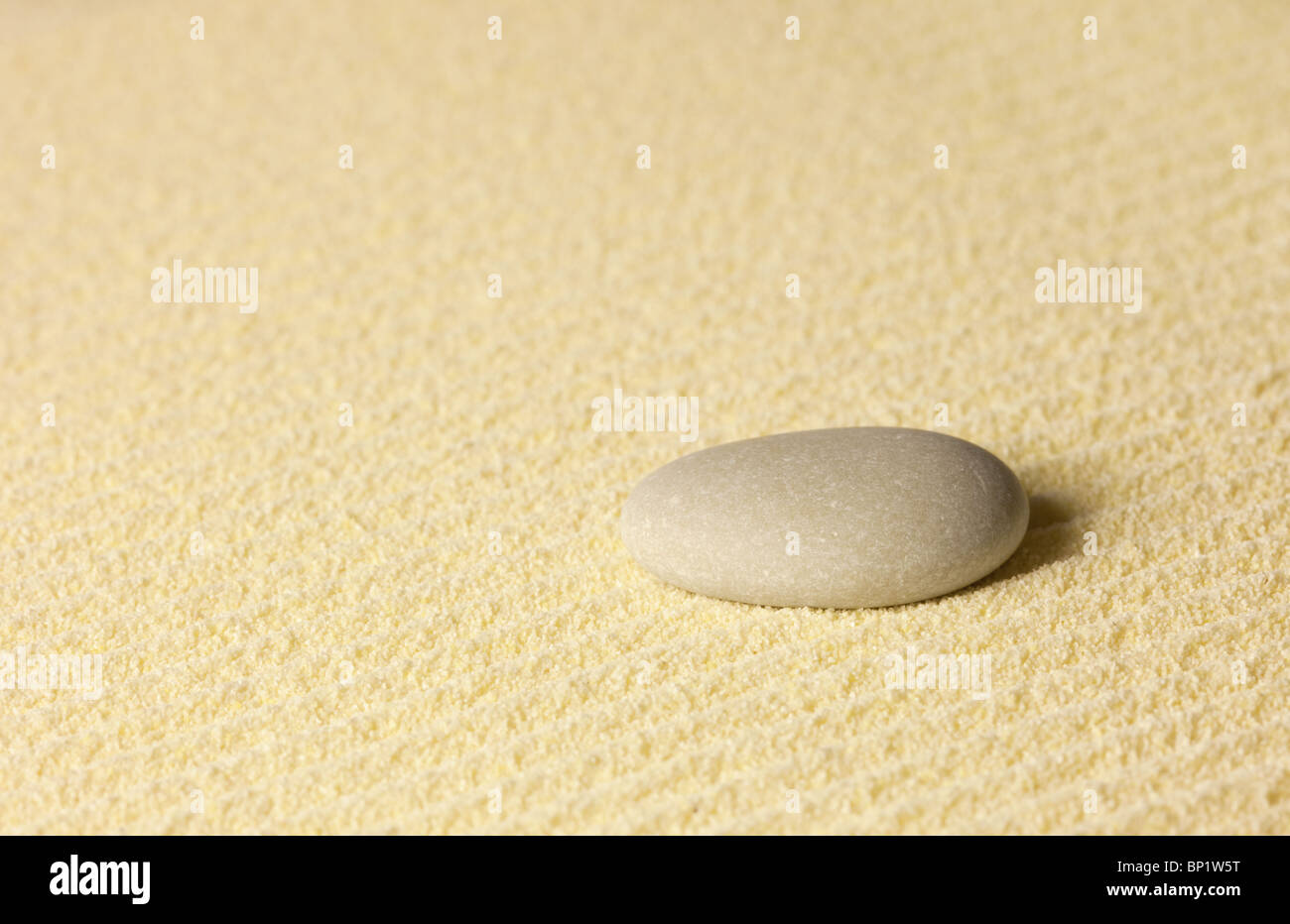 Element of a Japanese rock-garden - a small stone on sand Stock Photo