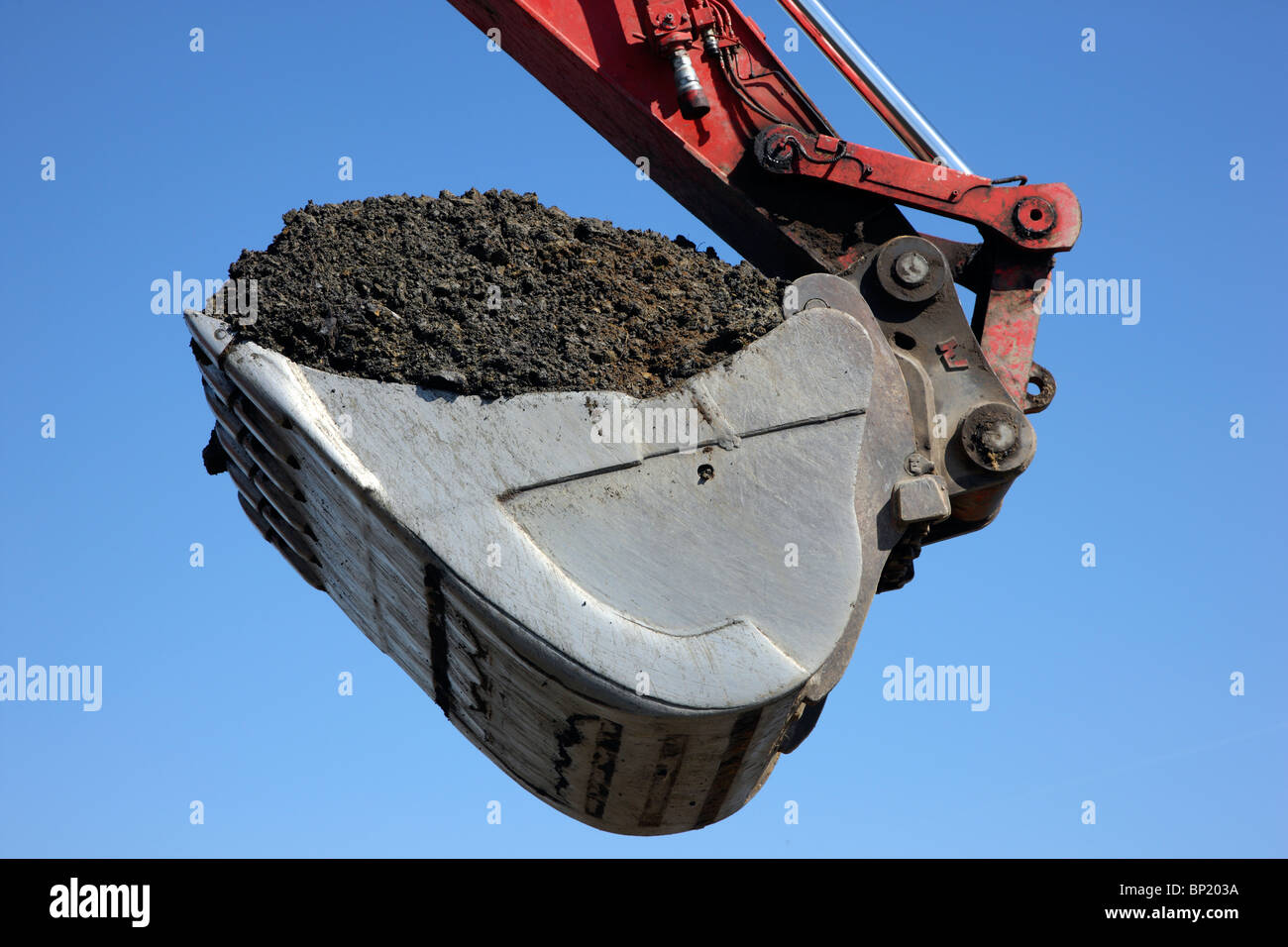 Excavator shovel, full with dark soil. Stock Photo