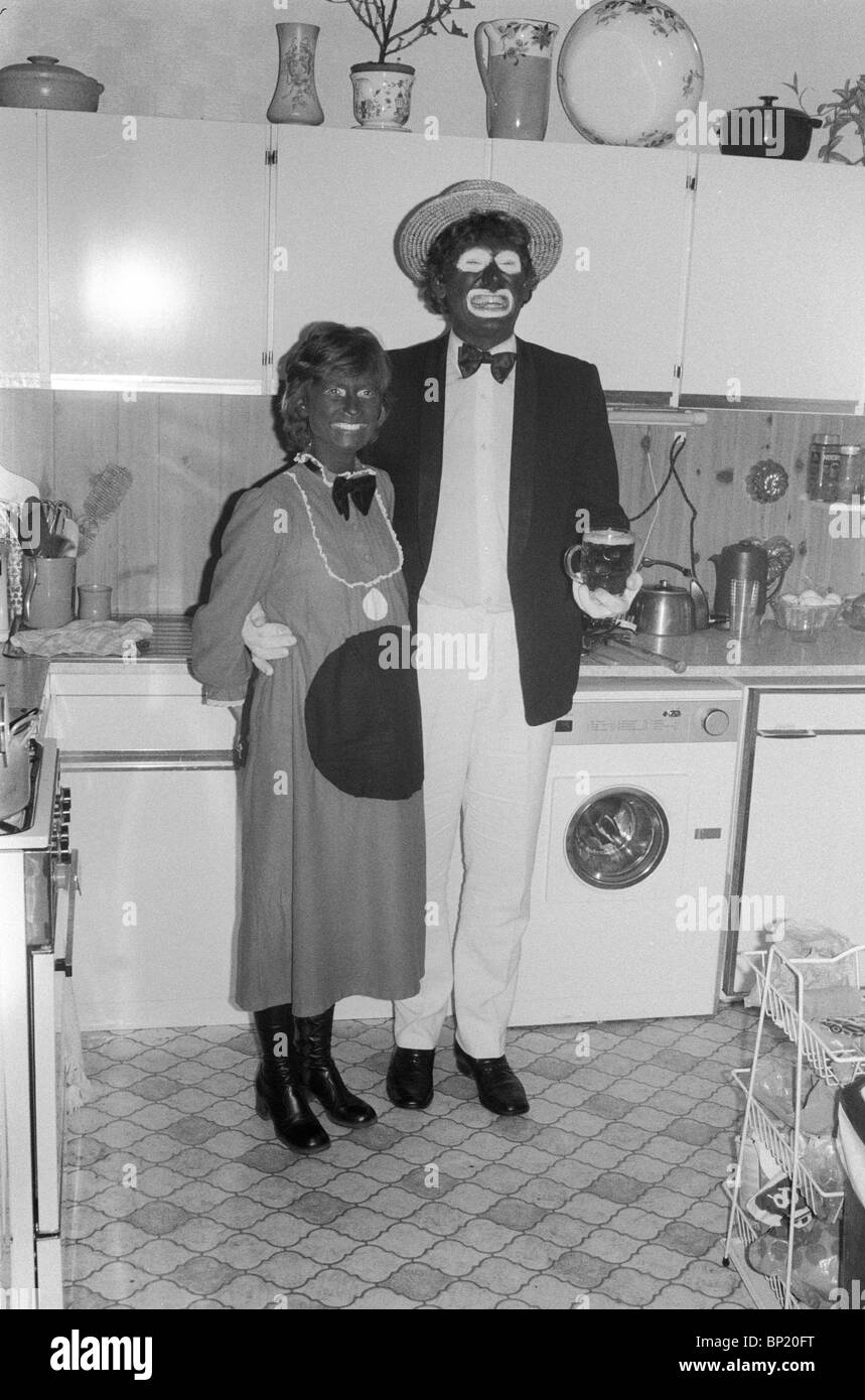 Blacked Up UK 1980s. A Christmas fancy dress party that was TV themed. The woman is dressed as Pot Black and her partner as one of the Black and White Minstrels. Both very popular television programmes of the day. Blackface couple paint their faces black at a fancy dress Christmas party.  West London, England December 1980. HOMER SYKES Stock Photo