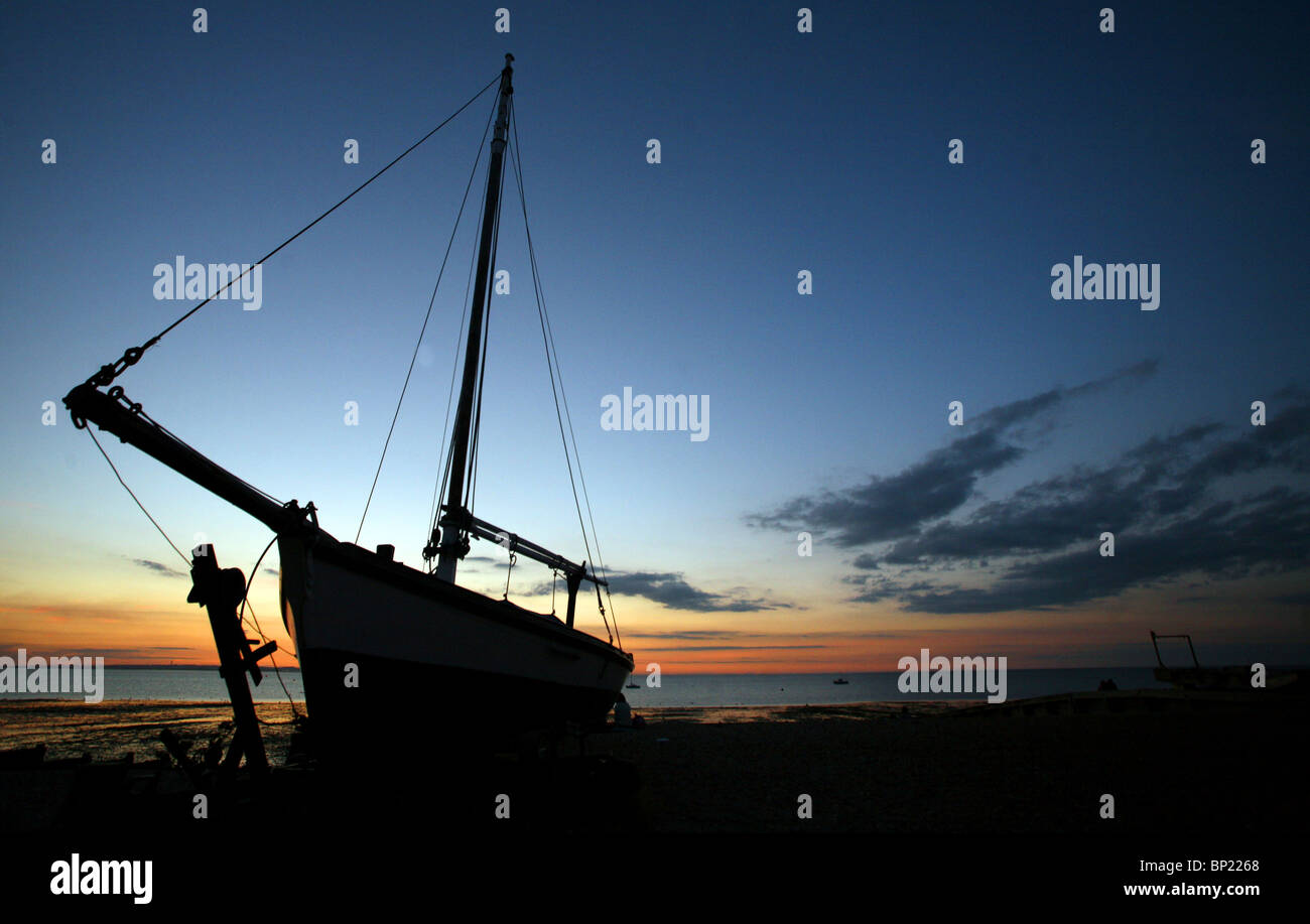 Silhouette of a fishing boat pictured at sunset on the beach in Whitstable. Stock Photo