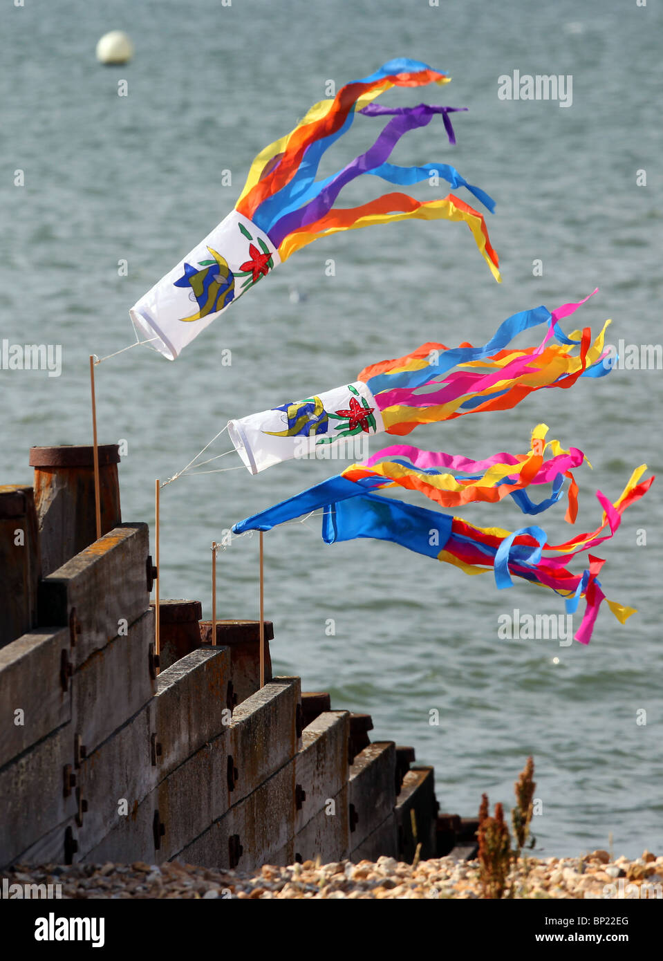 Colourful flags attached to sea groynes blowing in the wind in Whitstable, Kent. Stock Photo