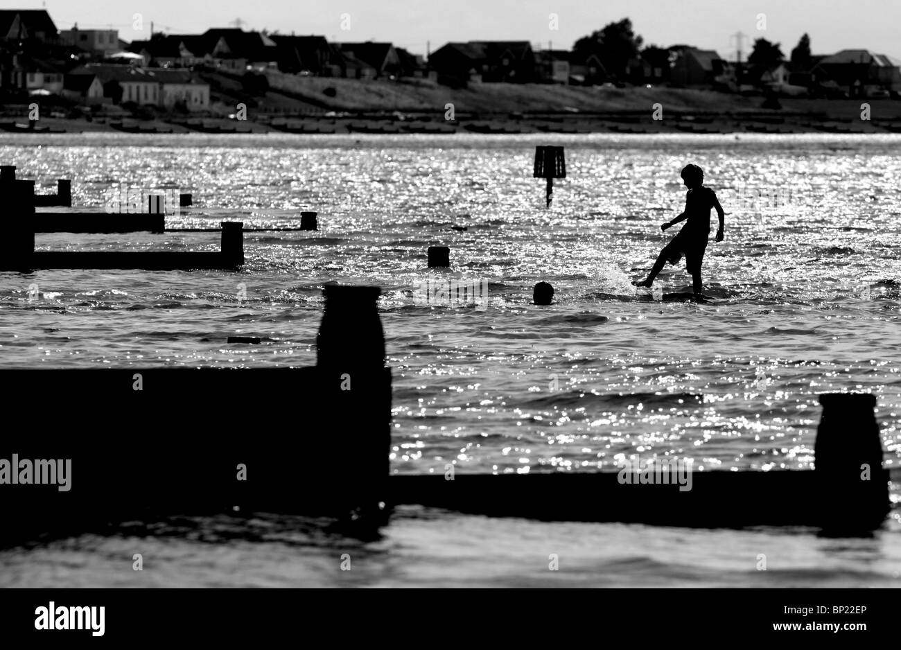 Silhouette of a child playing in the low tide in the sea in Whitstable, Kent, United Kingdom. Stock Photo